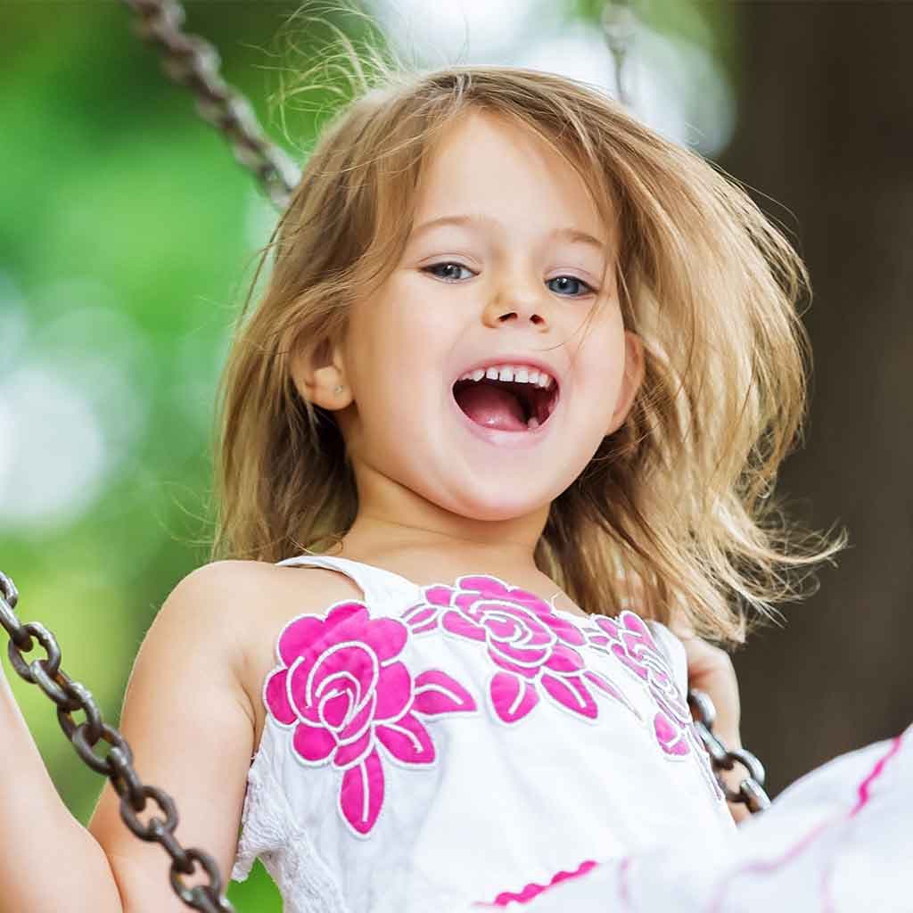 Young girl laughing on a swing