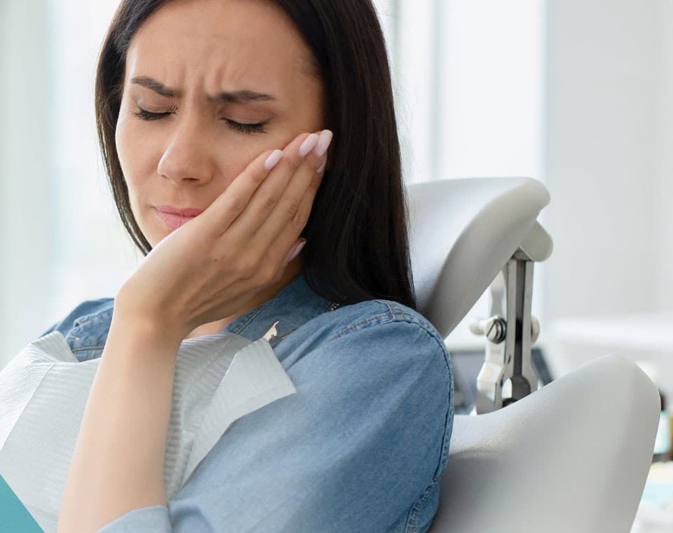 Woman holding her cheek in discomfort while waiting to be seen