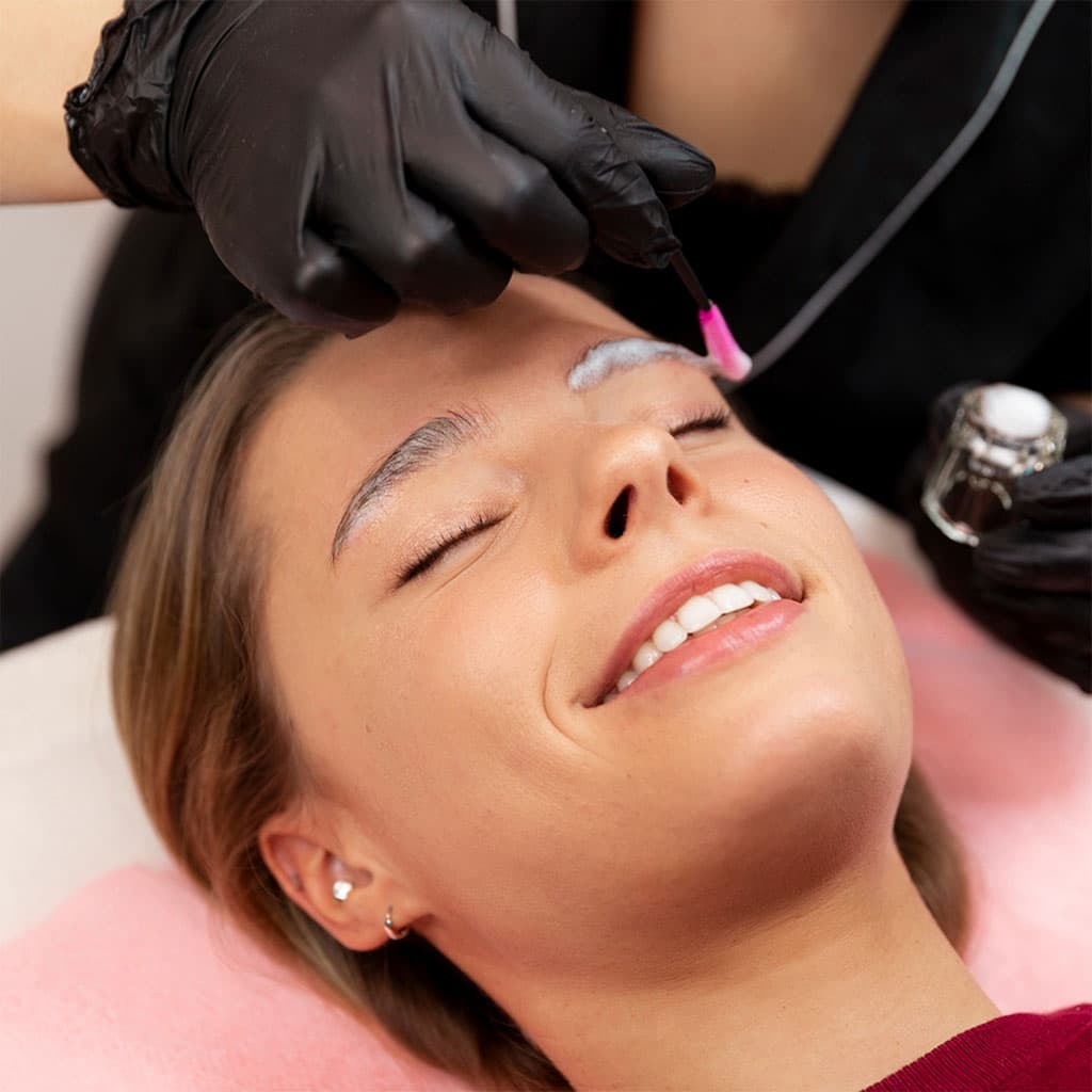 Technician shaping a client's eyebrows during microblading