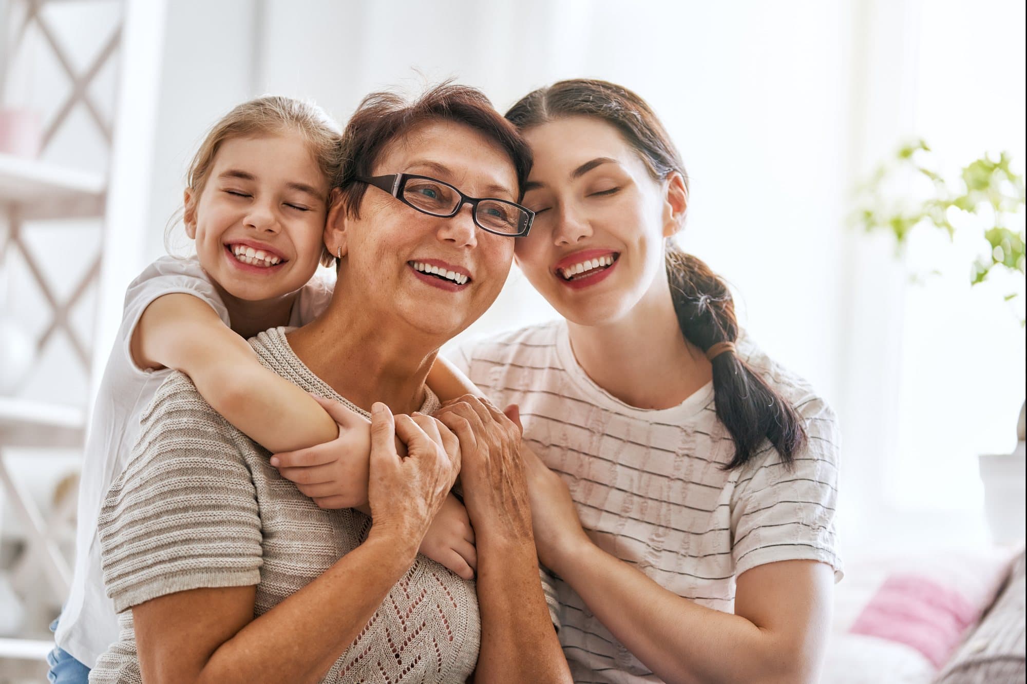 Grandmother, mother and daughter hugging and smiling at home